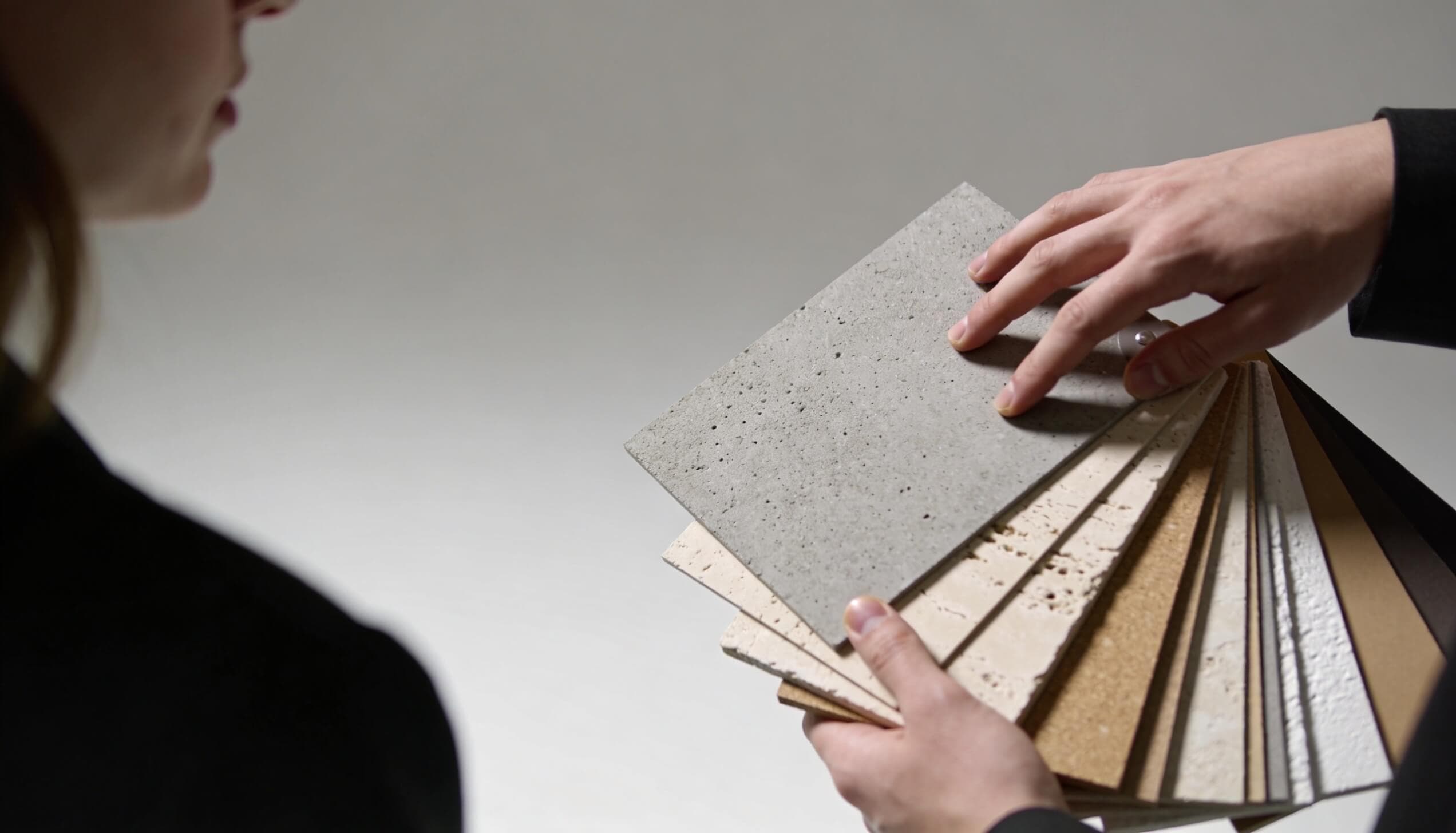 Plăci de probă cu tencuieli decorative, comparate în mână la lumină de studio